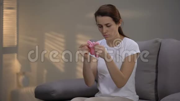 年轻女性绝望地看着粉红色的袜子拥抱它们不孕不育视频的预览图