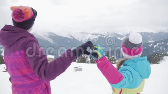 在冬天的度假村里母亲和孩子在做手的心充满爱意的家庭视频的预览图