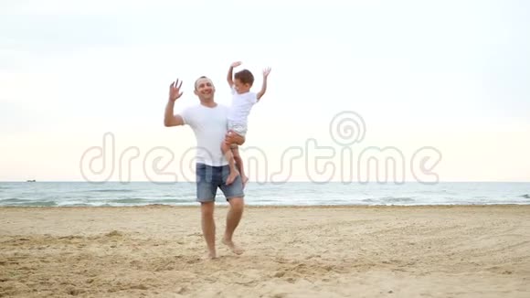 快乐的父子在阳光明媚的夏日在沙滩上放松爸爸把孩子抱在怀里情感是视频的预览图