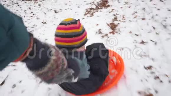 孩子和爸爸正在雪地里骑雪橇视频的预览图