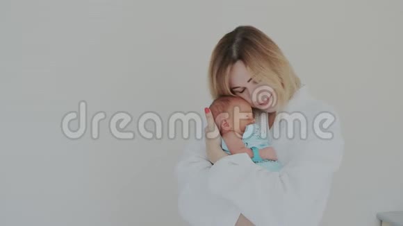 快乐的母亲拥抱她新生的婴儿抚摸他的手宝宝和妈妈在一起生育观念养育子女视频的预览图