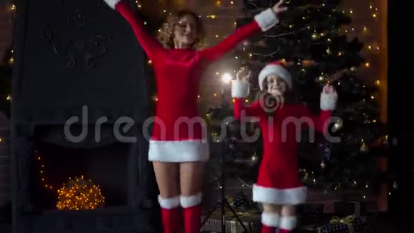 穿着圣诞服装的妈妈和女儿在圣诞树附近庆祝圣诞节视频的预览图