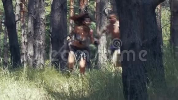 穿着皮革和毛皮衣服的野蛮女人正从树林里的一个男人那里跑出来视频的预览图