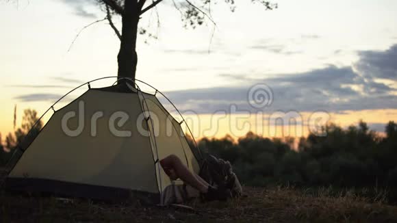 露营者早上从帐篷里出来伸伸懒腰打哈欠欣赏着替罪羊视频的预览图