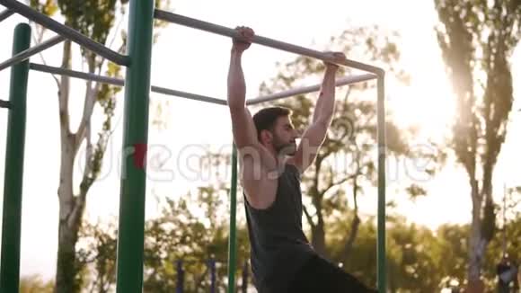 健身运动训练和人的概念年轻的胡须男子做腿拉同时挂在水平杆上视频的预览图