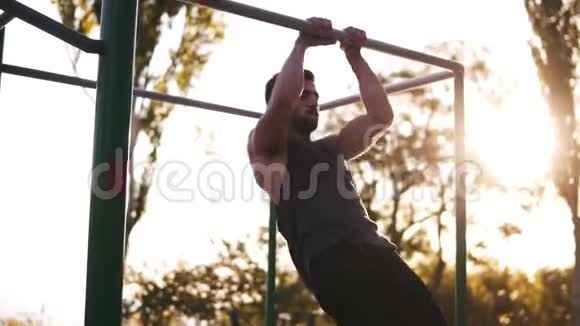 有胡子的健身男子在户外健身房锻炼手臂肌肉做下巴上的仰卧起坐作为交叉健身锻炼的一部分视频的预览图