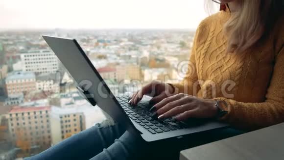 一位自由职业者在窗口拿着笔记本电脑可以看到城市景色视频的预览图