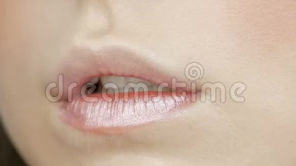 化妆师做化妆女孩模特口红遮光用特殊的刷子涂在嘴唇上近距离观看视频的预览图