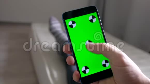 手部使用智能手机绿色屏幕躺在室内床垫上视频的预览图