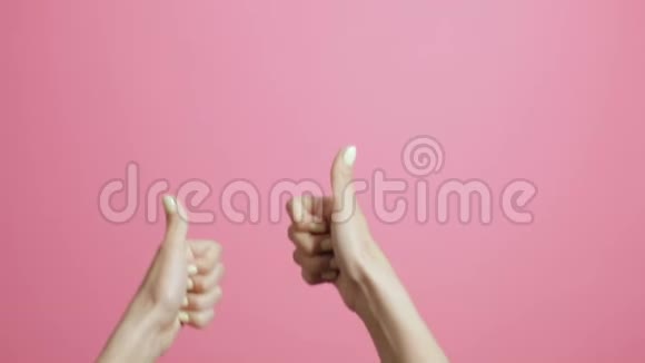 年轻女子双手竖起大拇指女孩在粉红工作室的背景上做手势班广告视频的预览图