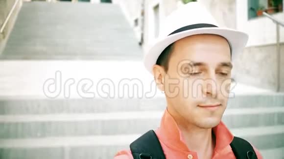 戴着帽子的男旅行者走在楼下的街道上视频的预览图