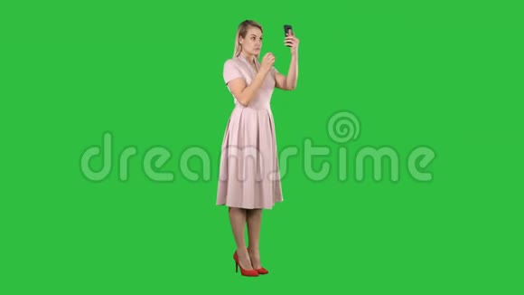 美女看着自己在她的智能手机固定她的头发在绿色屏幕铬钥匙视频的预览图