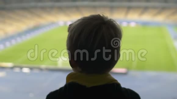 年轻男孩看着足球场梦想成为足球运动员视频的预览图