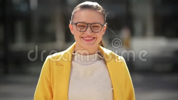 黄色外套中一个开朗微笑的年轻商务女性的肖像她在一个城市里有很好的心情度过时光视频的预览图