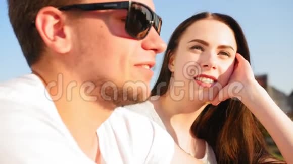 一对年轻快乐的夫妇的肖像浪漫的情侣在蓝天上聊天和坐着一起快乐关门视频的预览图
