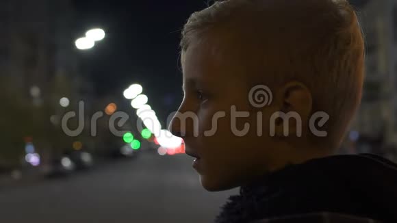 可怜的孤独男孩夜间站在城市街道收养中心的画像视频的预览图