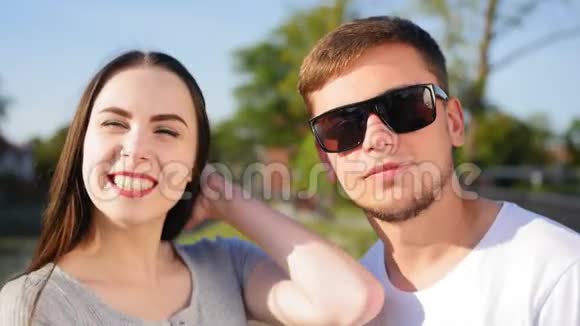 年轻幸福夫妇的肖像在池塘附近的绿色夏季公园里的浪漫情侣一起快乐近距离射击视频的预览图