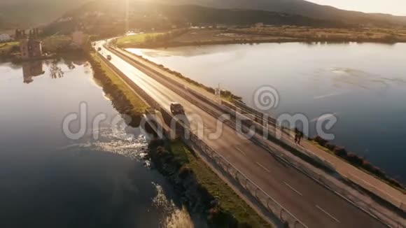 傍晚不明汽车沿着海上大坝行驶的空中跟踪拍摄意大利奥贝泰洛视频的预览图