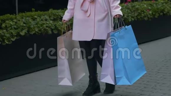 手里拿着纸袋的女士站在大街上站在商场正面绿色花坛的背景下视频的预览图