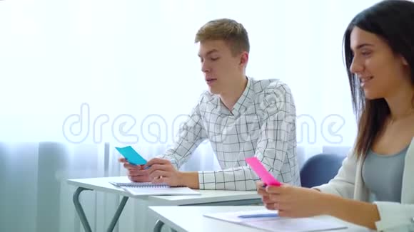 男女学生在高中课堂上拿彩色卡片讨论作业视频的预览图