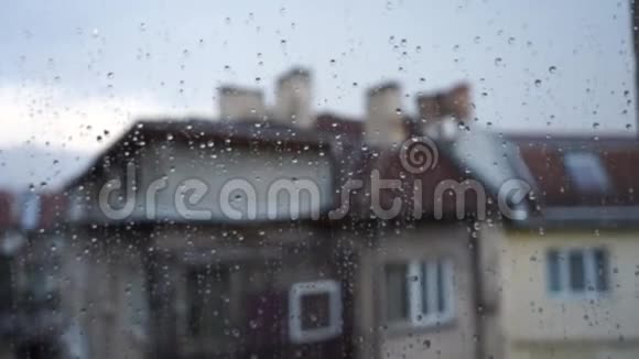 掉在窗玻璃上玻璃上水滴的特写雨和模糊的建筑背景阴天视频的预览图