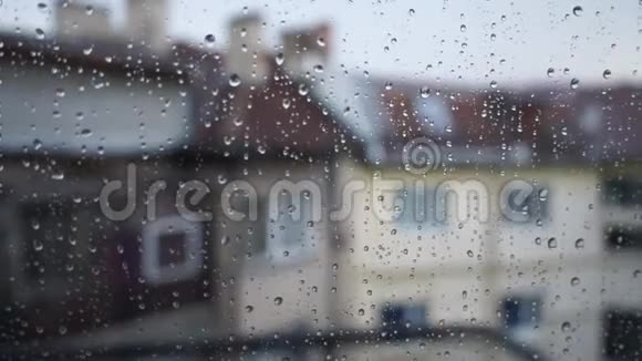 掉在窗玻璃上玻璃上水滴的特写雨和模糊的建筑背景阴天视频的预览图