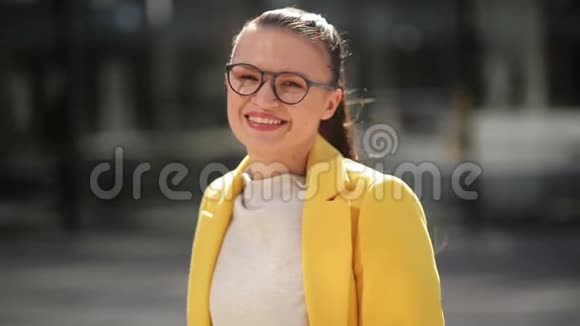 黄色外套中一个开朗微笑的年轻商务女性的肖像她在一个城市里有很好的心情度过时光视频的预览图