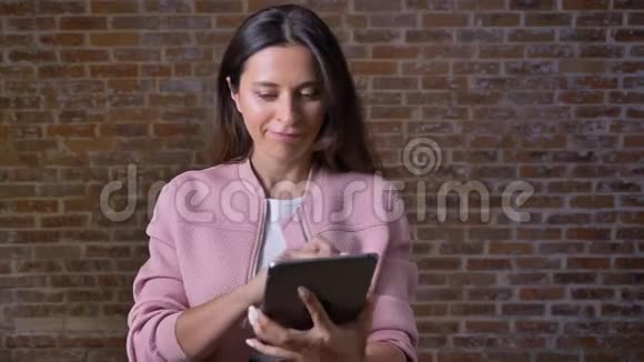快乐的令人敬畏的白种人女性正在她的平板电脑上显示绿色屏幕一只手指在上面站在上面视频的预览图