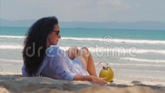 年轻的女人或快乐的女孩在海滩上晒日光浴享受海洋在阳光下喝椰子在阳光下放松视频的预览图