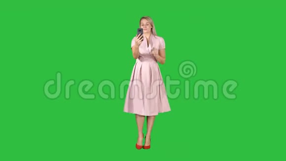 金发女人穿着粉红色的衣服自拍走在绿色屏幕上Chroma键视频的预览图