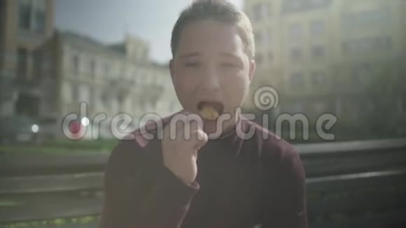 一个在户外长凳上吃薯片的笑男人视频的预览图
