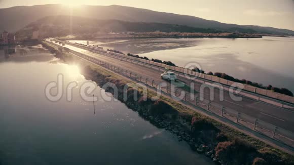 傍晚在海上沿着大坝行驶的不明汽车和自行车的鸟瞰图意大利奥贝泰洛视频的预览图