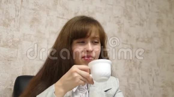 女商人坐在办公室的椅子上说着喝着白杯子里的咖啡笑着年轻女性视频的预览图