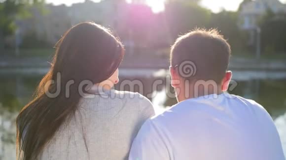 浪漫的夫妇坐在池塘附近的绿草上后景夫妻信任爱和幸福的理念近距离射击视频的预览图
