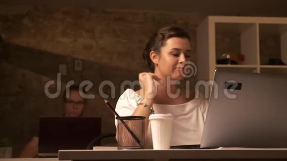 两个可爱的白种人工作女孩坐在笔记本电脑旁边打字一个专注的女人在砖头办公室喝咖啡视频的预览图