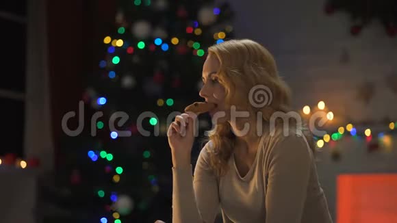 一位女士在圣诞树旁吃饼干上面覆盖着一块格子布咬着牙视频的预览图