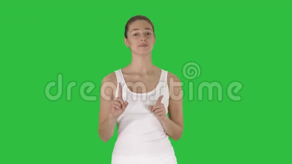 美丽的年轻女子穿着白色上衣在绿色屏幕上与相机交谈Chroma键视频的预览图