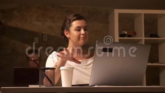 快乐的白种人女性正在喝咖啡一边看着电脑一边坐在她的同事旁边视频的预览图