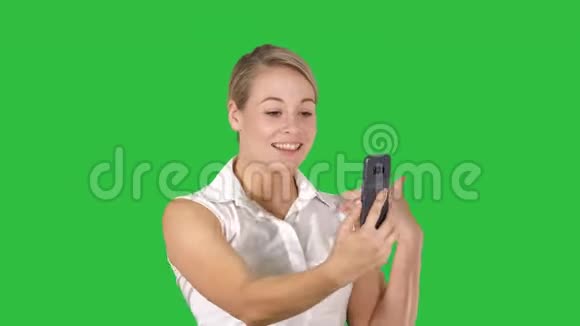 穿着粉红色的女人在智能手机上打视频电话走在绿色屏幕上Chroma键视频的预览图