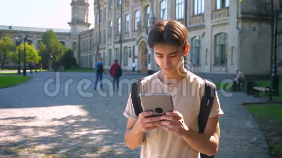 集中精力的亚洲男孩正在使用他的平板电脑同时站在古老的神奇城市阳光的斑点夏天的心情视频的预览图