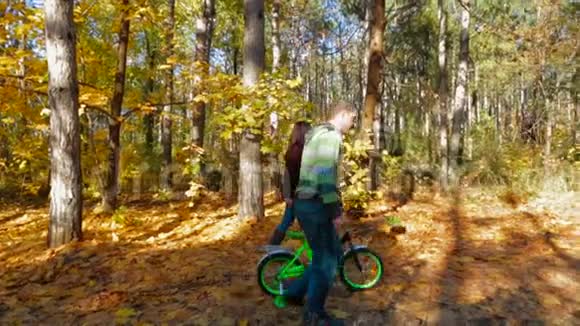 父母带着孩子自行车在森林里散步慢动作视频的预览图