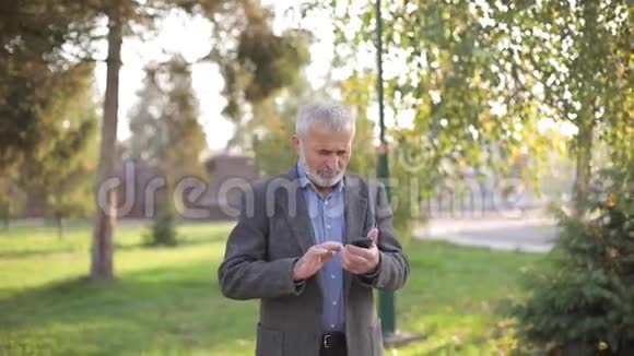 把留着白胡子的老人用外面的智能手机视频的预览图