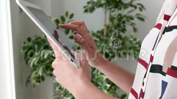 一个女人站在办公室时使用数字平板电脑的手视频的预览图