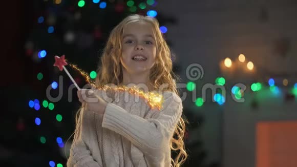 可爱的女孩用魔法棒创造奇迹圣诞装饰闪闪发光背后视频的预览图