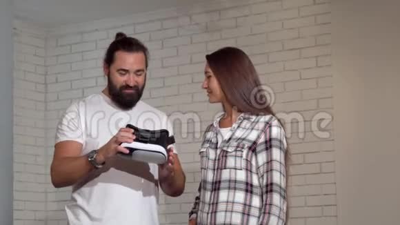 英俊的长胡子男人用虚拟现实眼镜看着他的女朋友视频的预览图