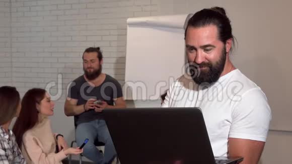 成熟的胡子商人使用笔记本电脑他的商业团队背景视频的预览图