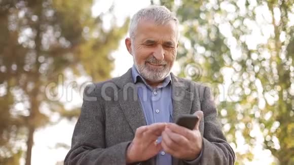 把留着白胡子的老人用外面的智能手机视频的预览图