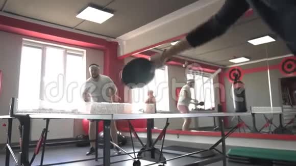 朋友一个留着胡子的男人和一个漂亮漂亮的女孩在新的健身房打乒乓球运动和健康慢视频的预览图