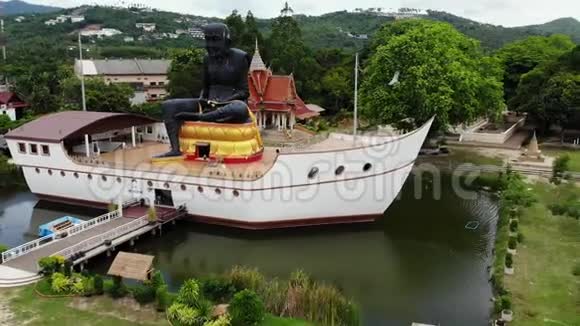 池塘里船上的黑色和尚雕像巨大的黑色和尚雕塑位于船形结构中间的小池塘上视频的预览图