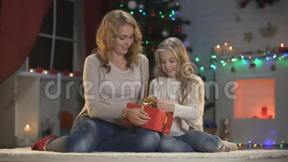 母亲和女儿为爸爸整理圣诞礼物拥抱准备视频的预览图